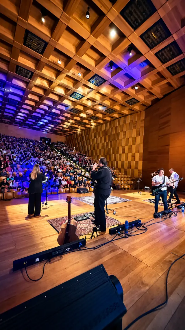 La banda vista desde atrás del escenario, frente al auditorio lleno